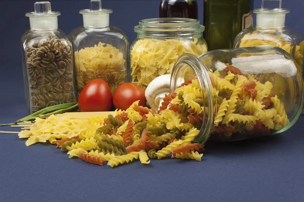 Diferentes tipos de pasta sobre la mesa, junto con verduras, listas para cocinar — Foto de Stock