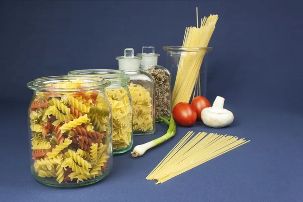 Diferentes tipos de pasta sobre la mesa, junto con verduras, listas para cocinar — Foto de Stock