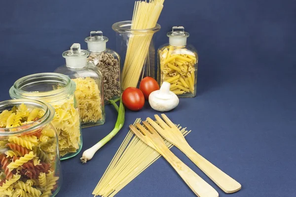 Diferentes tipos de pasta sobre la mesa, junto con verduras, listas para cocinar — Foto de Stock