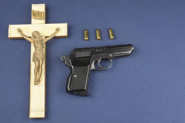 A wooden crucifix with the lettering INRI and gun, Faith and weapon defense of faith — Stock Photo, Image