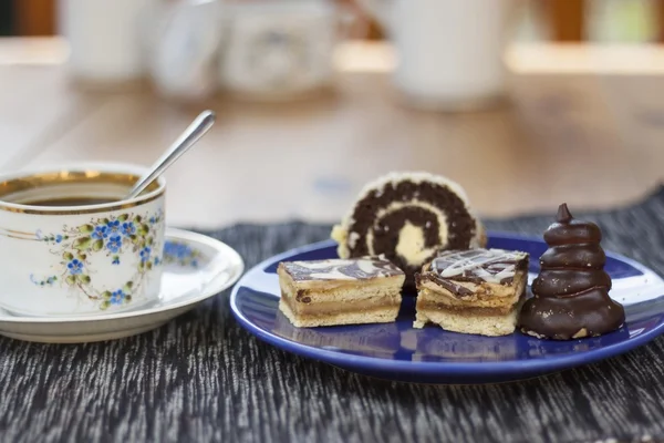 Десерт с кофе, шоколадные торты и рулоны на столе, размытый фон — стоковое фото