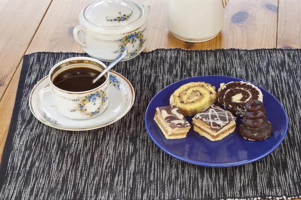 Десерт с кофе, шоколадные торты и рулоны на столе, размытый фон — стоковое фото