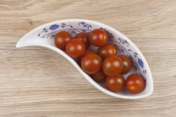 Tomates xerez em uma tigela de porcelana em fundo de madeira, alimentação saudável — Fotografia de Stock