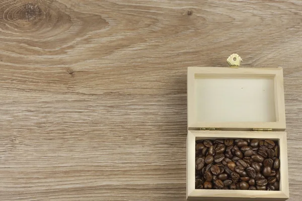 Granos de café en una caja de madera sobre un fondo de madera — Foto de Stock