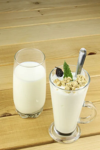 牛乳とヨーグルトとミューズリーのガラス木製のテーブルの上に立ちます。健康的な食事朝食. — ストック写真
