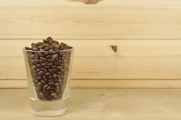 Glas met koffiebonen permanent op een houten plank. Close-up beeld van houten achtergrond. — Stockfoto