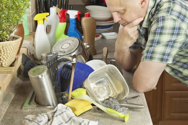 Чоловік миє брудний посуд у мийці на кухні. Прибирання вдома після вечірки . — стокове фото