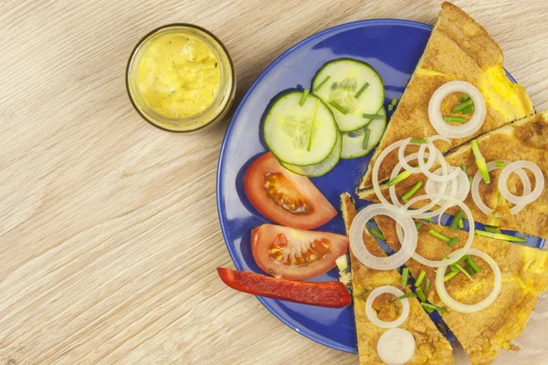 Scrambled egg omelet with vegetables on a wooden table. Preparation of fast food home. — Stock Photo, Image