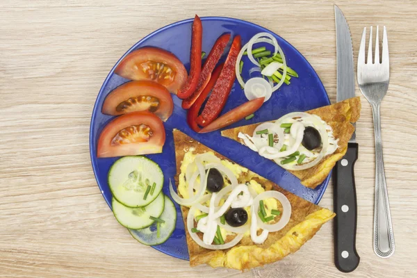 Rührei-Omelett mit Gemüse auf einem Holztisch. Zubereitung von Fast Food zu Hause. — Stockfoto