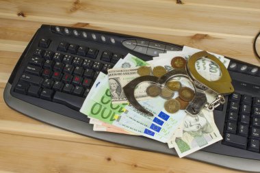 The concept of cybercrime. Criminal activity performed by computers and the Internet. Valid banknotes euro and the Czech koruna. Arrest cybercriminals, metal handcuffs and computer keyboard.