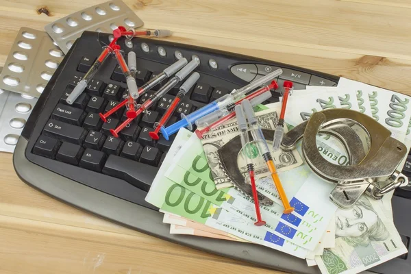 The concept of cybercrime. Illegal sales of medications and drugs over the Internet. Valid banknotes euro and the Czech koruna. Arrest cybercriminals, metal handcuffs and computer keyboard. — Stock Photo, Image