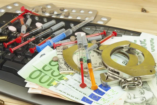 The concept of cybercrime. Illegal sales of medications and drugs over the Internet. Valid banknotes euro and the Czech koruna. Arrest cybercriminals, metal handcuffs and computer keyboard. — Zdjęcie stockowe