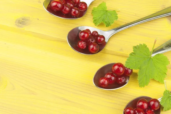 Coffee spoon with red currants on a yellow wooden table. Preparing for home baking currant dessert. — Stock Photo, Image