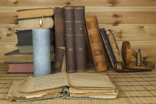 A estudar história. Livros antigos em cima da mesa, a ler à luz das velas. Contentamento com um cachimbo em um café enquanto lê livros antigos . — Fotografia de Stock