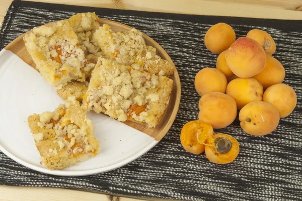 Домашний абрикосовый торт на тарелке. Свежесобранные абрикосы на деревянном столе. Домашний десерт из летних фруктов . — стоковое фото