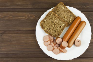 Small poultry sausages from poultry meat and whole wheat bread with sunflower seeds. Quick to prepare food on a wooden table.