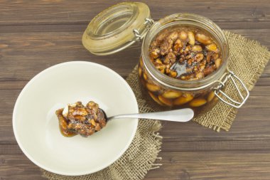 Jar of honey and nuts. Sweet treat for snacking. Pickled walnuts in honey. The ingredients for the sweet taste of dessert.