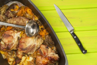 Casserole dish with pork on a wooden board. Homework communal meal. Carving roasts, prepare meals.