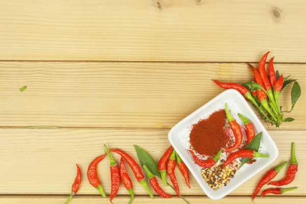 Spices in a ceramic bowl. Freshly picked chili peppers on a wooden table. Preparation for the domestic processing of a crop. Decoration of chilli peppers. Place for text menu. Healthy fresh food.