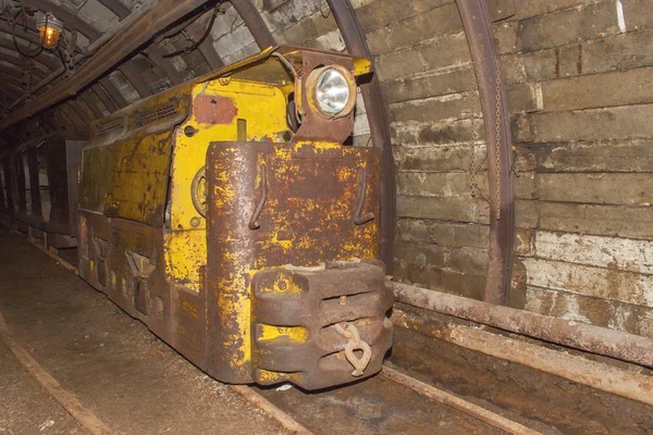 Uma velha mina de carvão abandonada e um comboio de minas. Mineração de carvão na mina subterrânea. Comboio mineiro para transportar mineiros até ao ponto de extracção. Transportes subterrâneos . — Fotografia de Stock