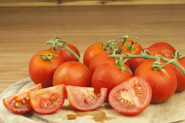 Fresh tomatoes on the kitchen table. Tomatoes on a wooden cutting board. Domestic cultivation of vegetables. Fresh organic food ready to cook. Fresh dietary ingredients. Raw vegetables to raw food. — Stock fotografie