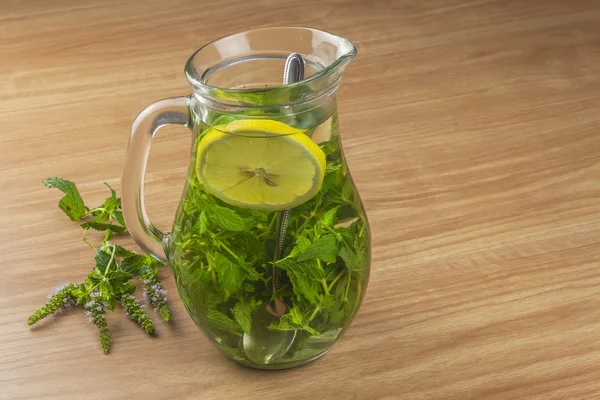 Fresh homemade mint tea. Tempting summer refreshment. Healthy, refreshing drink without sugar. Peppermint tea in a glass jar with lemon. Preparing tea. — Stock Photo, Image