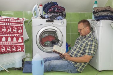 Bir erkek giyim çamaşır makinesine yıkar. Ev işi erkekler. Adam karısını ne zaman çamaşır yardım. Ev işleri bölümü. Adamın yanına çamaşır makinesi