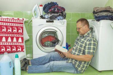 Bir erkek giyim çamaşır makinesine yıkar. Ev işi erkekler. Adam karısını ne zaman çamaşır yardım. Ev işleri bölümü. Adamın yanına çamaşır makinesi