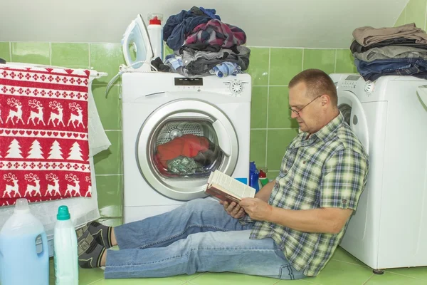 Um homem lava roupa na máquina de lavar roupa. Homens do trabalho doméstico. Homem ajudando sua esposa ao lavar roupas. A divisão do trabalho doméstico. Homem perto da máquina de lavar roupa — Fotografia de Stock