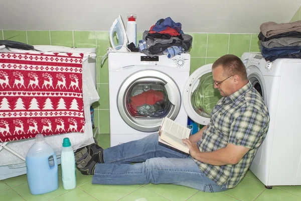 Um homem lava roupa na máquina de lavar roupa. Homens do trabalho doméstico. Homem ajudando sua esposa ao lavar roupas. A divisão do trabalho doméstico. Homem perto da máquina de lavar roupa — Fotografia de Stock