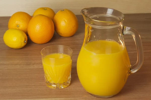 Domestic fresh orange juice in a glass jar on a wooden table. — Stock Photo, Image