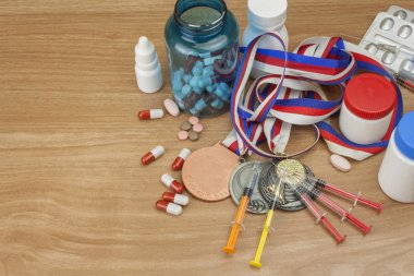 Sporda doping. Spor için anabolik steroid kötüye. Anabolik steroidler ahşap bir masaya döküldü. Dolandırıcılık spor. İlaç endüstrisi. Spor dolandırıcılık, sahte kazanan.