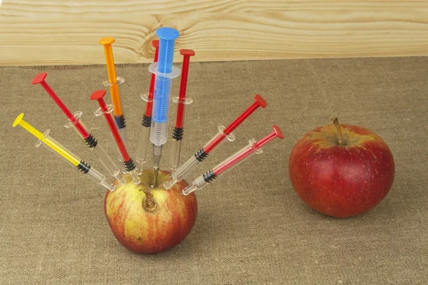 Genetic modification concept. Fruit and syginge. Apple receiving an injection of some substance for rapid ripening. Chemistry in the agricultural industry. Apple and syringe. — Stock Photo, Image