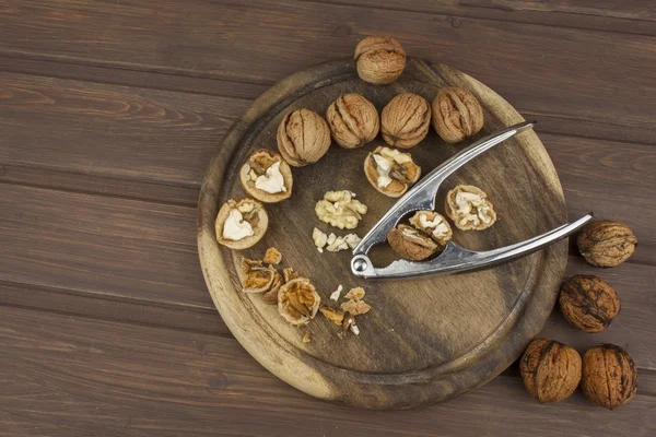 Peeling fresh walnuts, walnut dessert preparation. Walnuts on the kitchen table. Healthy food. Walnut kernels and whole walnuts on table. — Stock Photo, Image