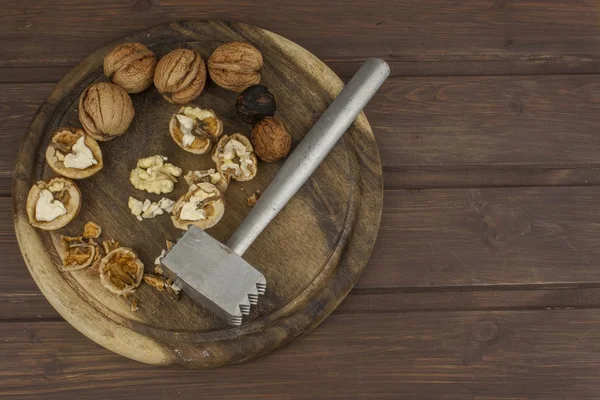 Peeling fresh walnuts, walnut dessert preparation. Walnuts on the kitchen table. Healthy food. Walnut kernels and whole walnuts on table. — Stock Photo, Image