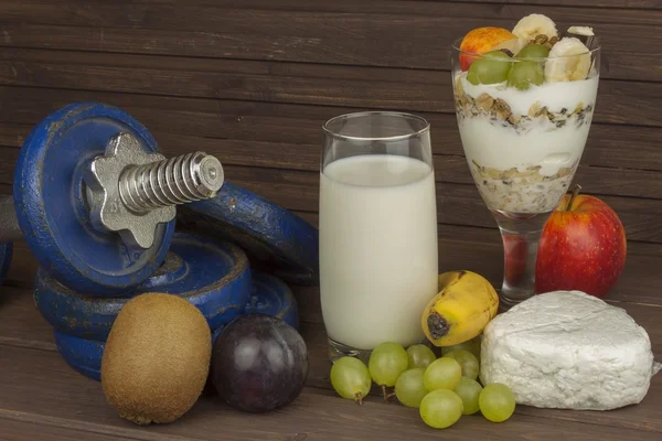 Ernährung für Sportler baut Muskelmasse auf. Proteinsnack. Milchprodukte und Hanteln. frische Milch im Glas und Müsli-Frühstück auf einem Holztisch. Haferflocken mit Milch und Quark, Mahlzeiten für Sportler — Stockfoto