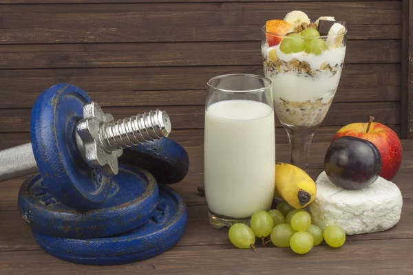 Diet for athletes build muscle mass. Protein snack. Dairy products and dumbbells. fresh milk in the glass and muesli breakfast on a wooden table. Oatmeal with milk and curd, meals for athletes