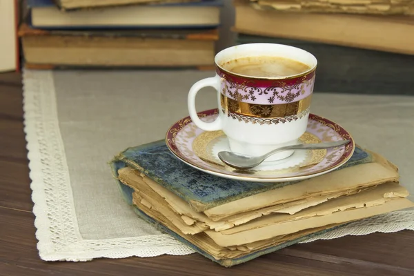 コーヒーと古書の磁器のカップ。コーヒーを飲みながらおくつろぎください。古い本を読む. — ストック写真