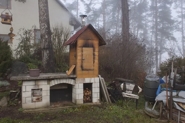 Házi smokehouse a reggeli ködben. Hazai termelés kolbász. A ház az erdőben a Smokehouse. Hagyományos ételek — Stock Fotó