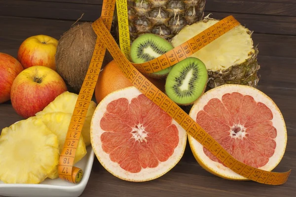 Vörös grapefruit és gyümölcs a fogyás. Friss étrend sportolók. Gyümölcs, egy fából készült asztal. Összetétele friss gyümölcsöket, különböző. Kiegyensúlyozott étrend. Egzotikus gyümölcsök széles választékát. — Stock Fotó