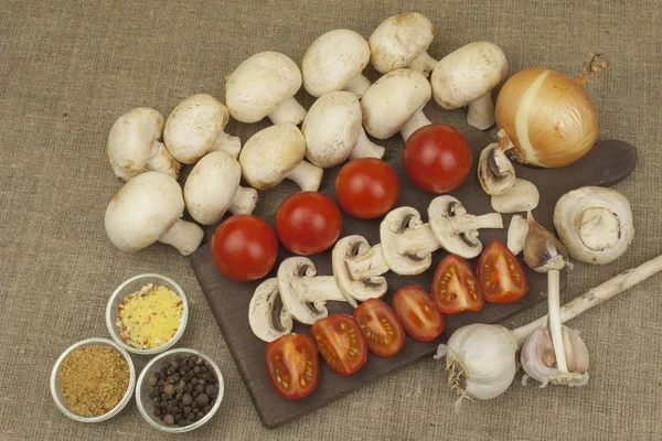 Raw mushrooms on a cutting board. Preparation of Champignons in the kitchen. Spices for food preparation. Vegetables to prepare meals