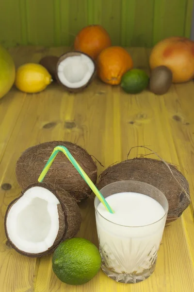 Coco agrietado sobre mesa de madera amarilla. Preparando bebida refrescante de coco. Bebida tropical. La mesa del bar de la playa. Una bebida refrescante hecha de leche de coco . — Foto de Stock