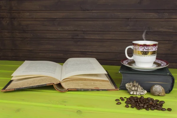 Чашка горячего кофе и старая книга. Расслабляюсь перед кофе. Изучаю старые книги. Место для смс. Чашка кофе на деревянном столе. Старые старинные книги на деревянном столе с чашкой кофе . — стоковое фото