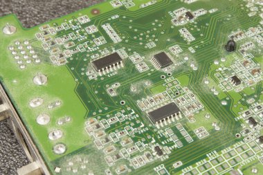 A dusty green computer component. Detail of a dusty computer mainboard. Electronic components on the printed circuit board. clipart