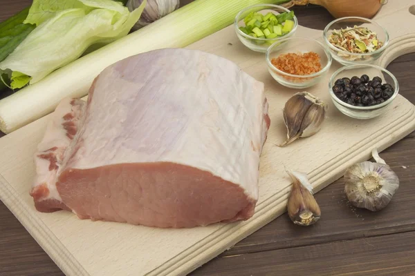 Porc cru frais sur une planche à découper avec des légumes et des épices, préparation de viande pour la cuisson — Photo