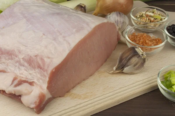 Porc cru frais sur une planche à découper avec des légumes et des épices, préparation de viande pour la cuisson — Photo