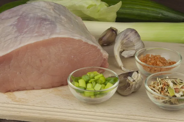 Porc cru frais sur une planche à découper avec des légumes et des épices, préparation de viande pour la cuisson — Photo