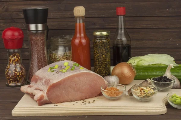 Porc cru frais sur une planche à découper avec des légumes et des épices, préparation de viande pour la cuisson — Photo