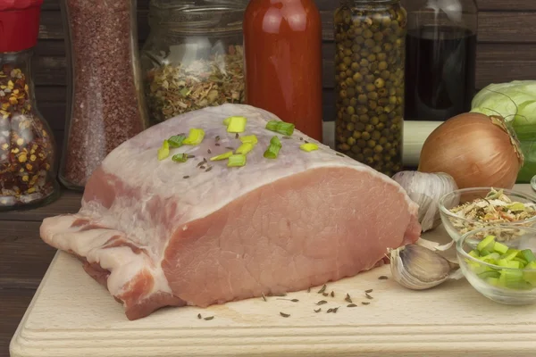 Porc cru frais sur une planche à découper avec des légumes et des épices, préparation de viande pour la cuisson — Photo