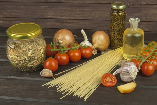 Preparación de pasta casera. Pasta y verduras en una mesa de madera. Alimento dietético. Pastas, tomates, cebolla, aceite de oliva y albahaca sobre fondo de madera . — Foto de Stock